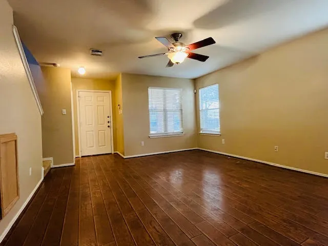 a view of an empty room with wooden floor and a window