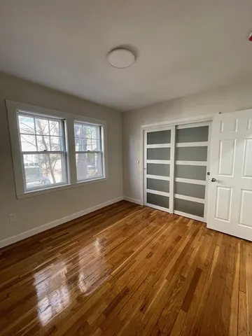 a view of an empty room with a window and wooden floor