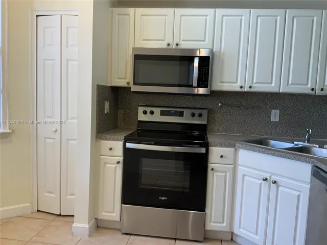a kitchen with granite countertop a refrigerator and a stove top oven