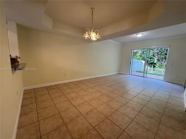 a view of an empty room and chandelier fan