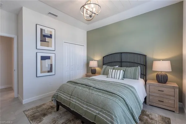 a bedroom with a bed and a lamp on dresser