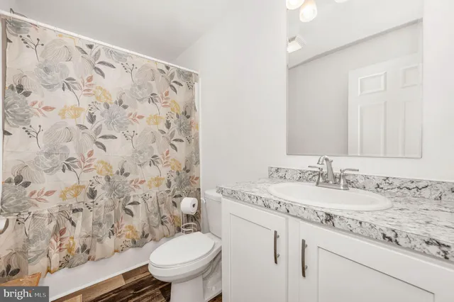 a bathroom with a granite countertop sink a toilet and a mirror