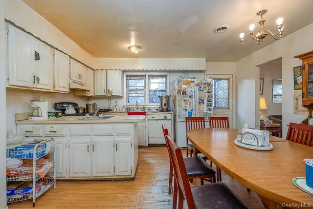 a kitchen with stainless steel appliances granite countertop a stove top oven a sink a dining table and chairs with wooden floor