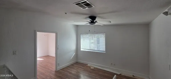 a view of an empty room with wooden floor and windows