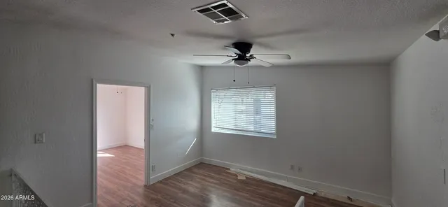 a view of an empty room with wooden floor and windows