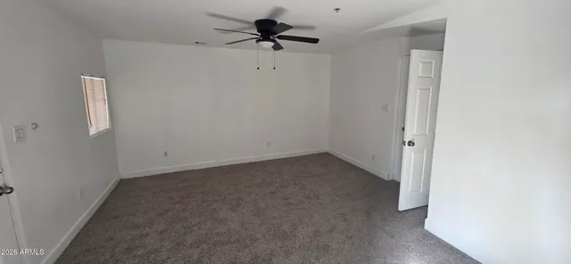 an empty room with a window and a fan