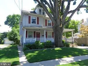 a view of a brick house next to a yard with big trees