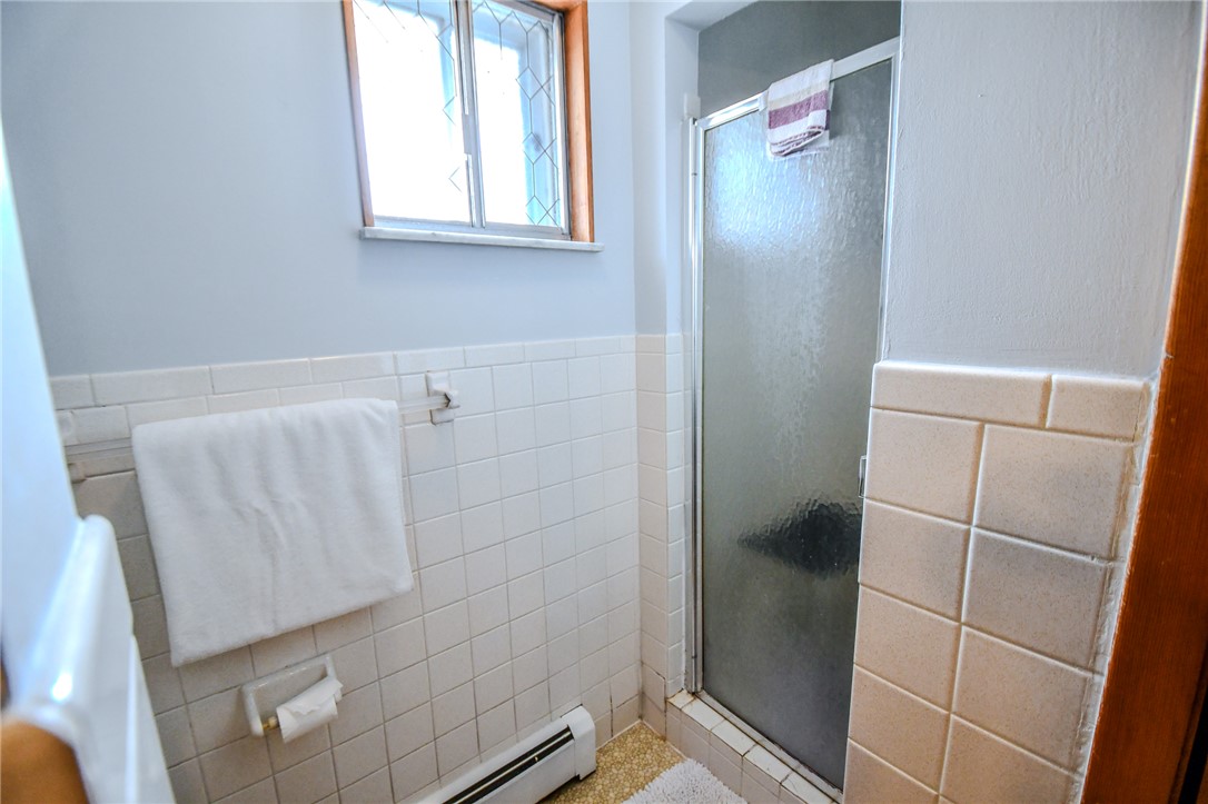 10833 Kendig Road Medway, OH 45341 - Photo 24 of 46 This bright bathroom offers a glass-enclosed shower and tiled walls, creating a clean and functional space.