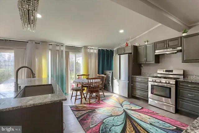 a kitchen with stainless steel appliances granite countertop a stove top oven a sink dishwasher and cabinets with wooden floor