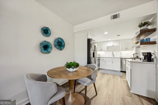 a kitchen with a dining table chairs and white cabinets