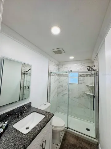 a bathroom with a granite countertop sink toilet mirror and shower