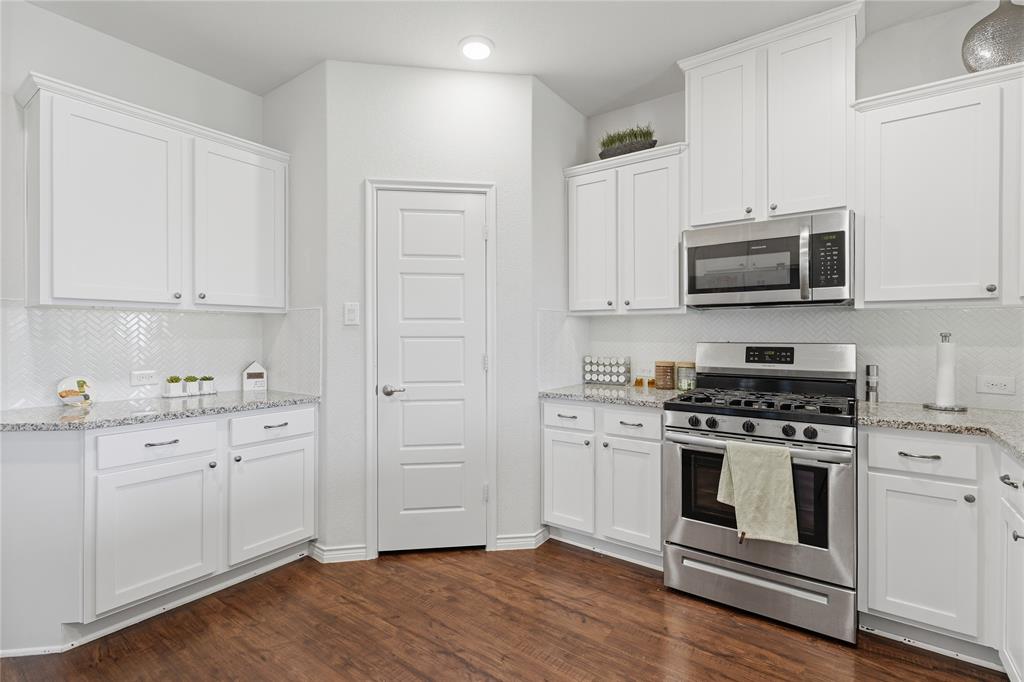 10101 Travis Road Little Elm, TX 75068 - Photo 13 of 26 a kitchen with cabinets stainless steel appliances and wooden floor