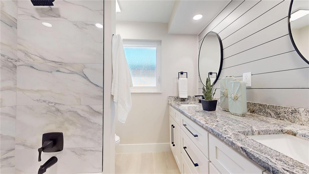 6380 3rd Palm Point St. Pete Beach, FL 33706 - Photo 22 of 48 a bathroom with a granite countertop sink a mirror and shower