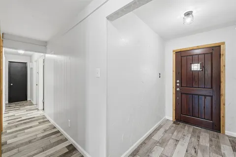 a view of a hallway with wooden floor and closet area