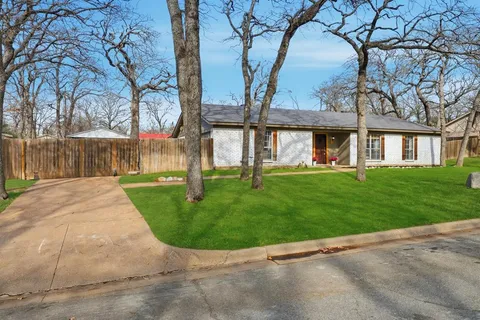 front view of house with a yard and palm trees