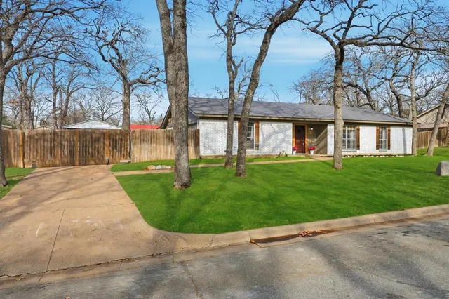 front view of house with a yard and palm trees