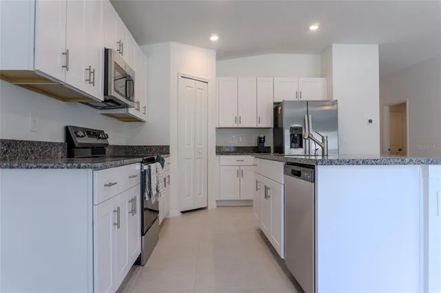 a kitchen with stainless steel appliances granite countertop white cabinets and a sink
