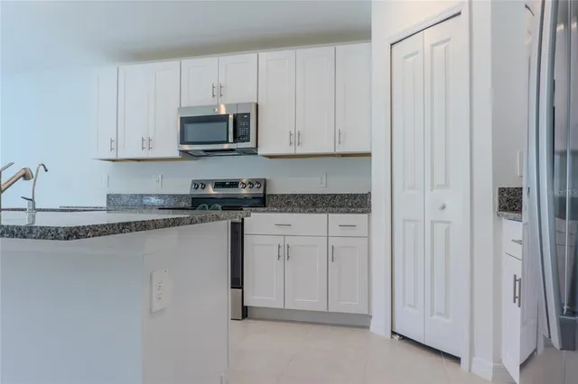 a kitchen with a refrigerator and white cabinets