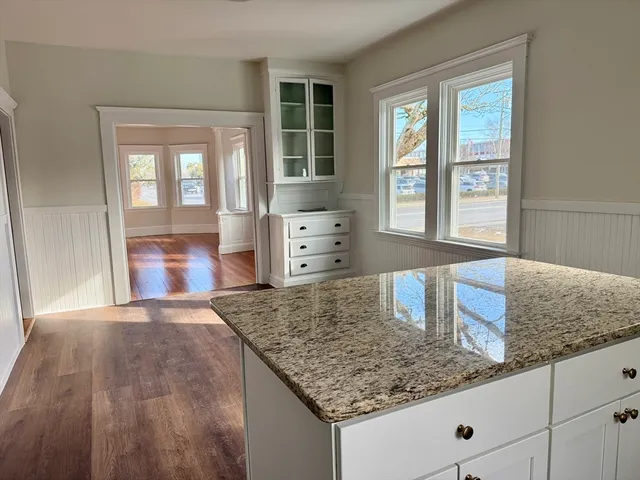 a kitchen with kitchen island a counter top space a sink granite counter tops and a large window