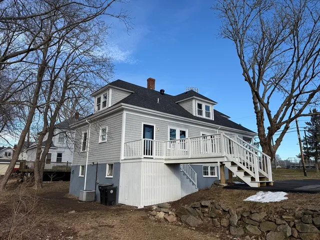 a view of a white house with a large tree