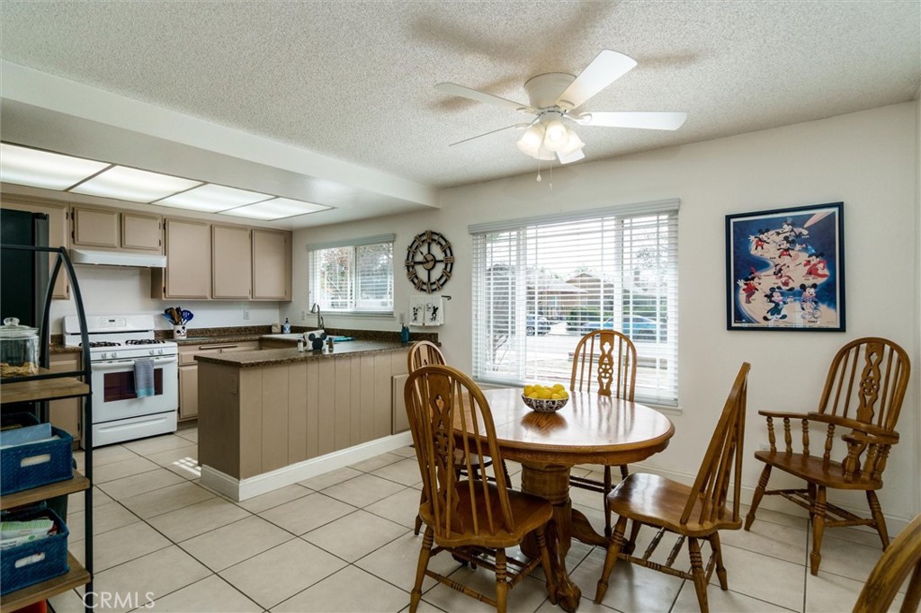 27062 Terrytown Road Menifee, CA 92586 - Photo 13 of 36 a kitchen with stainless steel appliances granite countertop a stove a sink dishwasher a dining table and chairs with wooden floor