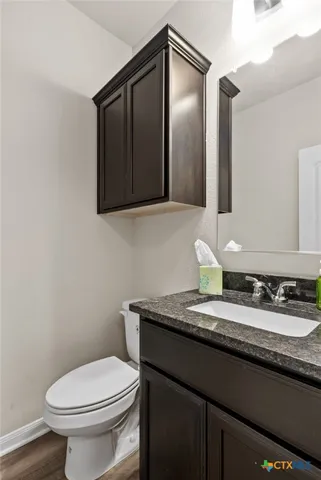 a bathroom with a granite countertop toilet sink and mirror