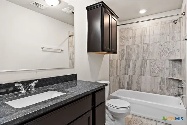 a bathroom with a granite countertop sink toilet and shower
