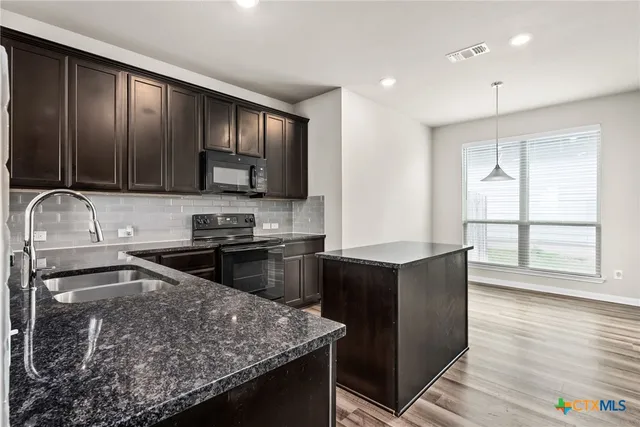 a kitchen with granite countertop wooden cabinets and a stove top oven