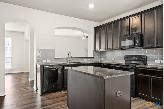 a kitchen with kitchen island granite countertop a sink cabinets and stainless steel appliances