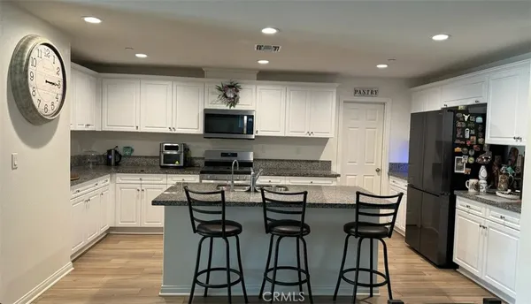 a kitchen with cabinets a sink a stove a refrigerator and a clock