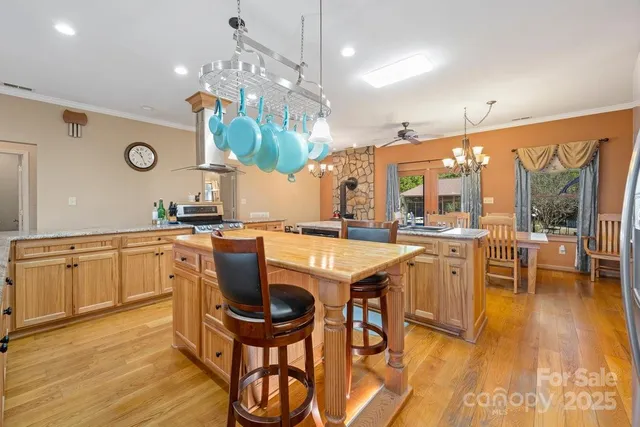 a kitchen with stainless steel appliances granite countertop a kitchen island a stove a table and chairs in it