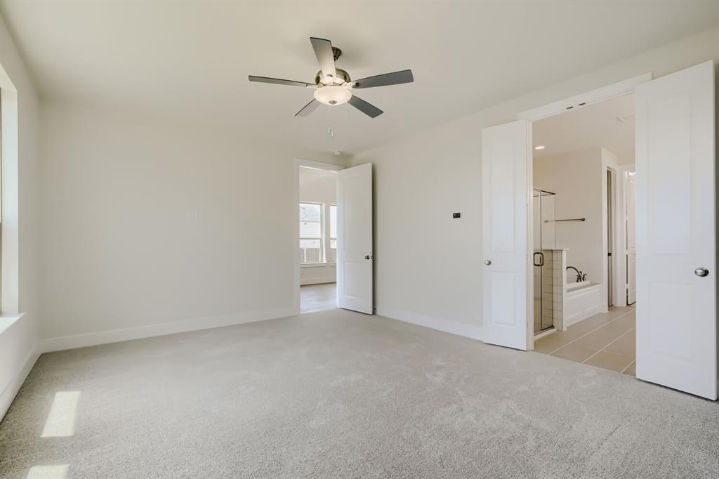 828 Stone Grv Road Lavon, TX 75166 - Photo 11 of 27 Carpeted room featuring a ceiling fan with integrated lighting, a window, and two paneled doors opening to a bathroom with a glass-enclosed shower and a bathtub