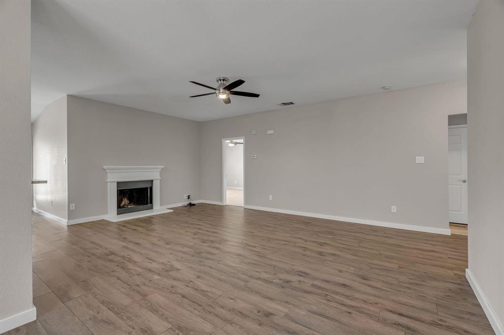 3920 Cane River Road Fort Worth, TX 76244 - Photo 19 of 22 a view of an empty room with wooden floor fireplace and a window