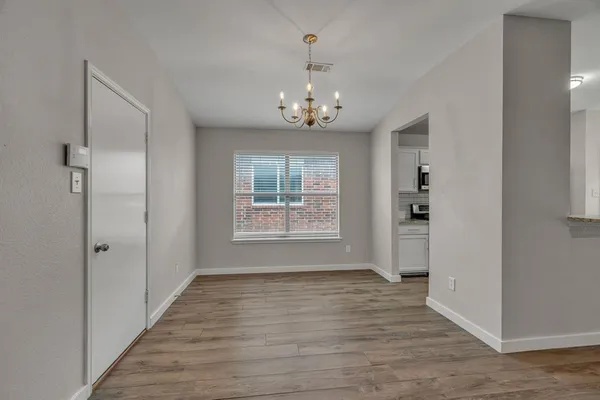 an empty room with wooden floor fireplace and windows