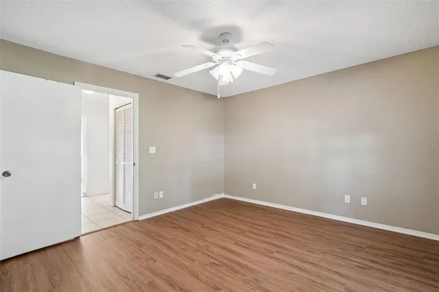 a view of empty room with wooden floor and fan