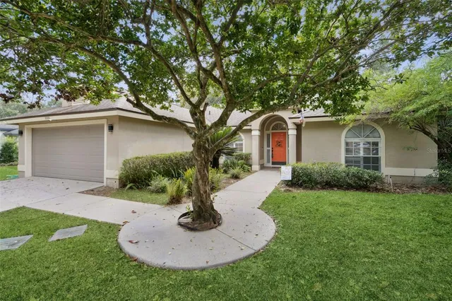 a front view of a house with a yard garage and tree
