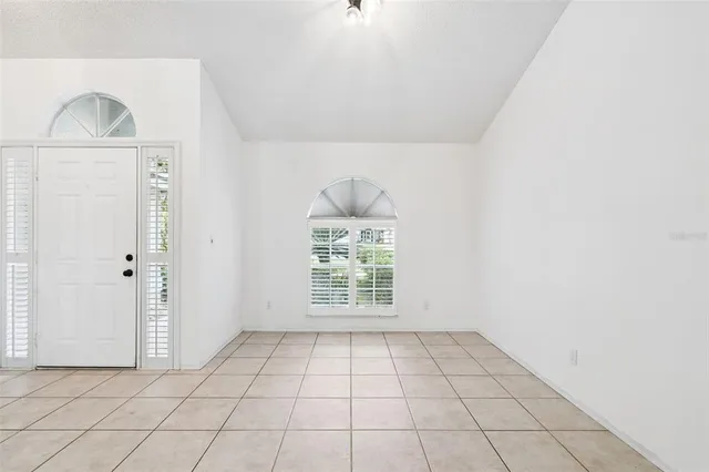 a view of kitchen and empty room with wooden floor