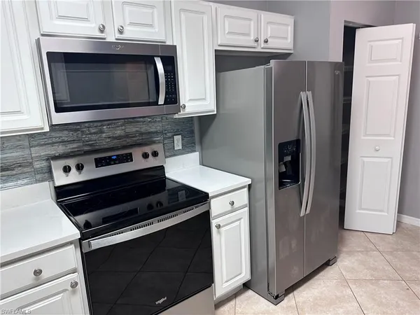 a kitchen with granite countertop a refrigerator stove and microwave