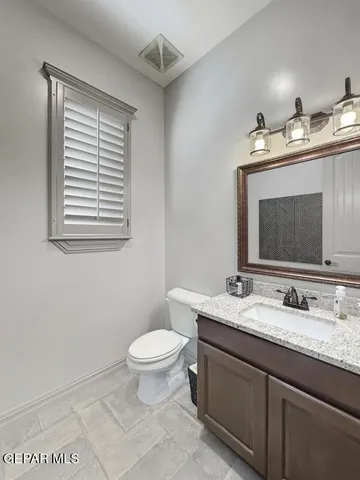a bathroom with a granite countertop sink toilet and mirror