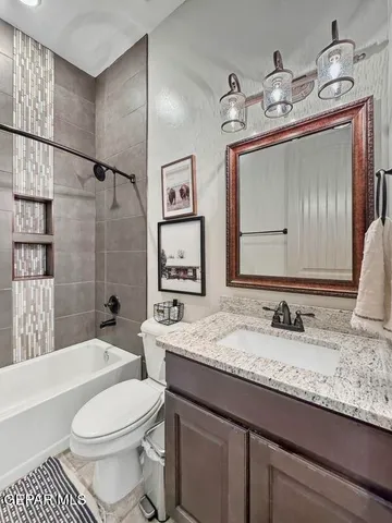 a bathroom with a granite countertop sink a toilet and shower