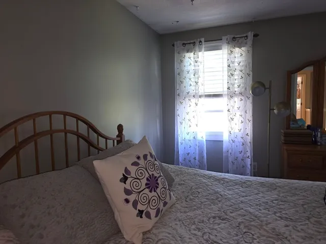 a bedroom with a bed and a lamp on the dresser