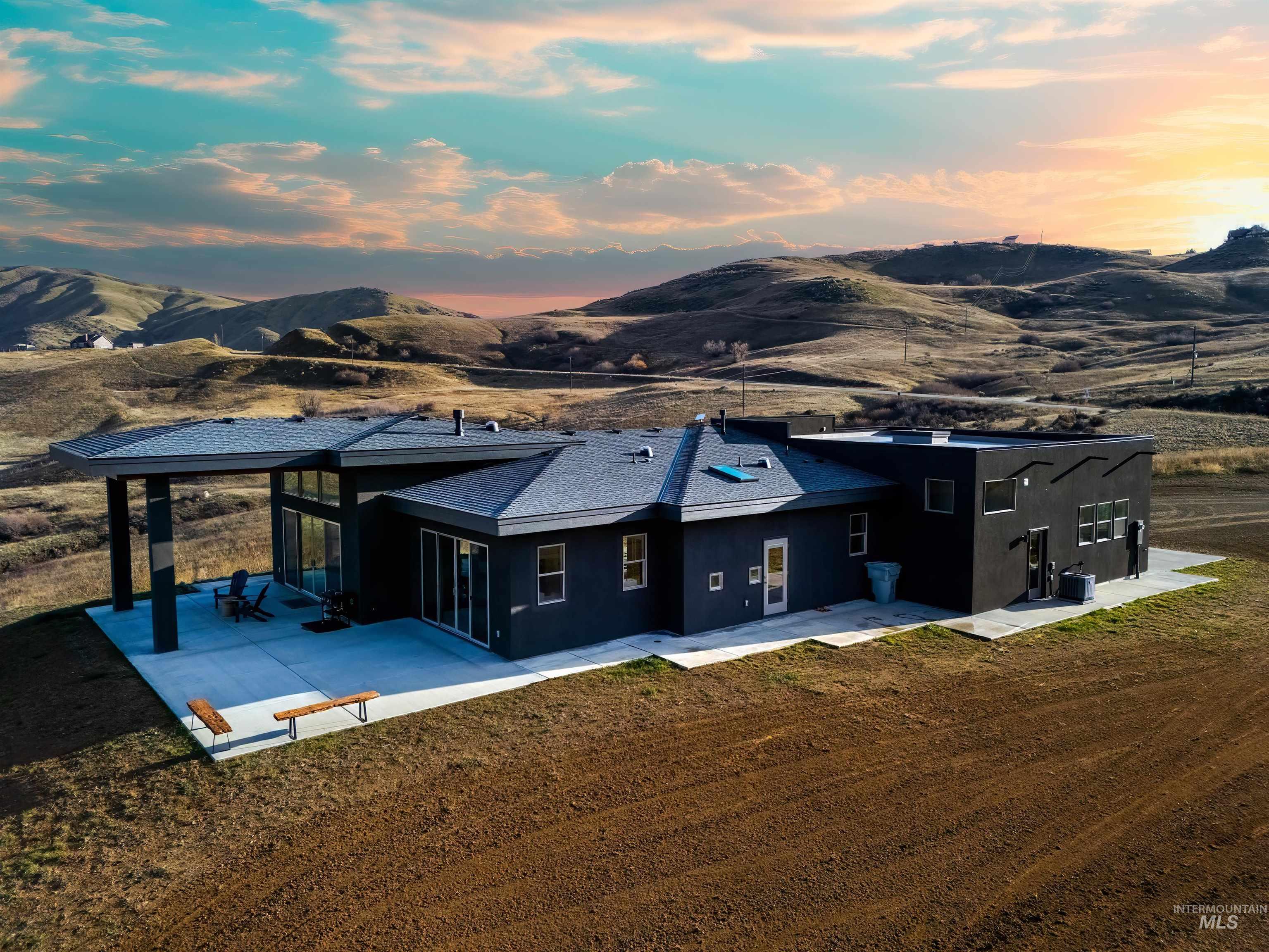 170 Summit Ridge Road Horseshoe Bend, ID 83629 - Photo 40 of 50 Back of house at dusk with stucco siding, a sunroom, a mountain view, and a patio