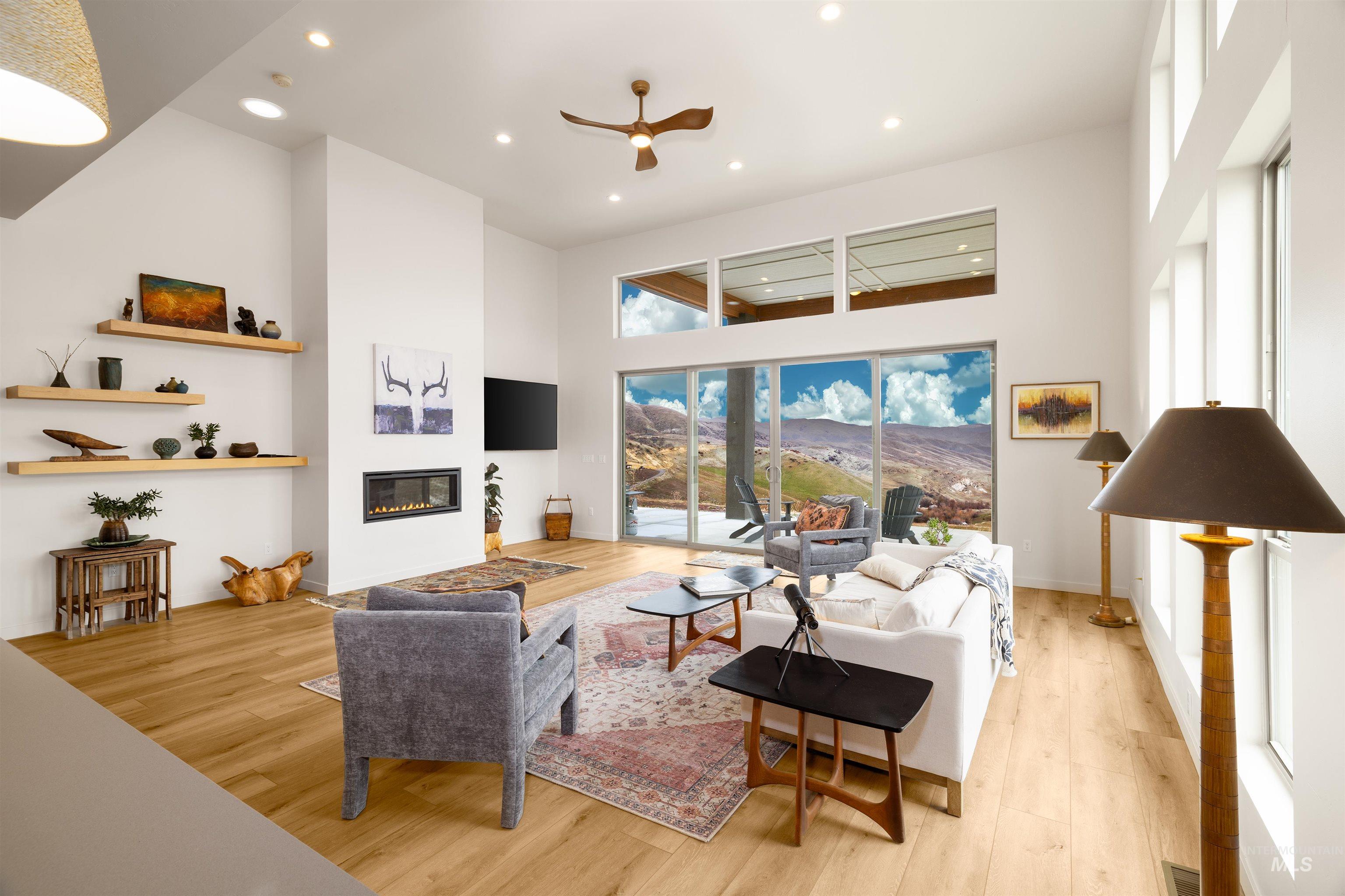 170 Summit Ridge Road Horseshoe Bend, ID 83629 - Photo 9 of 50 Living area featuring a towering ceiling, light wood finished floors, a glass covered fireplace, ceiling fan, and recessed lighting