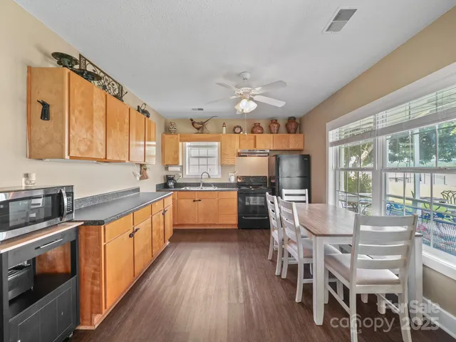 a kitchen with stainless steel appliances granite countertop a stove top oven a sink dishwasher a dining table and chairs with wooden floor