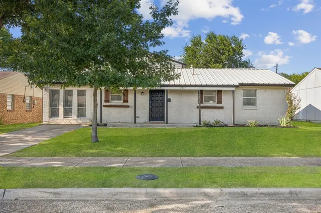 a backyard of a house with plants and large tree