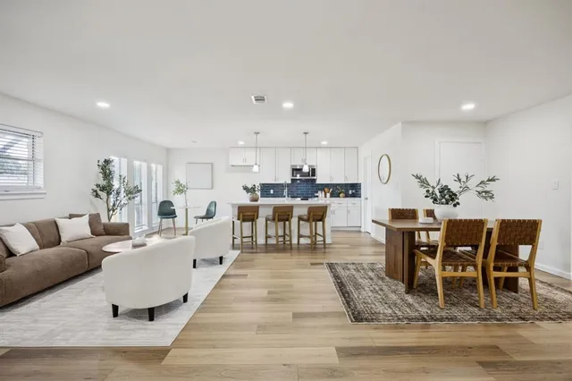 a living room with furniture a dining table and kitchen view with wooden floor