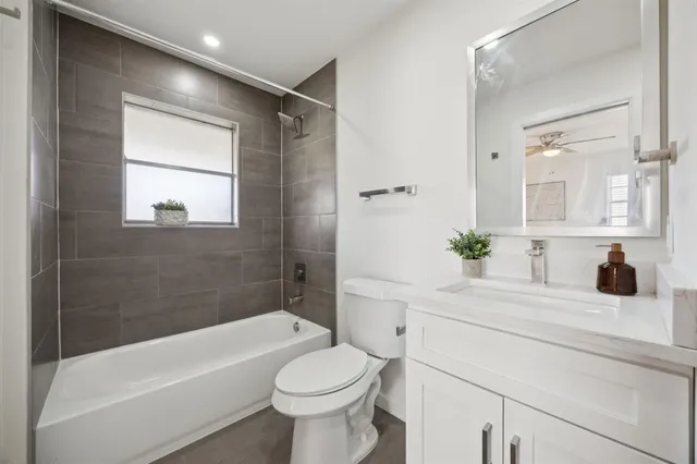 a bathroom with a bathtub shower sink vanity mirror and toilet