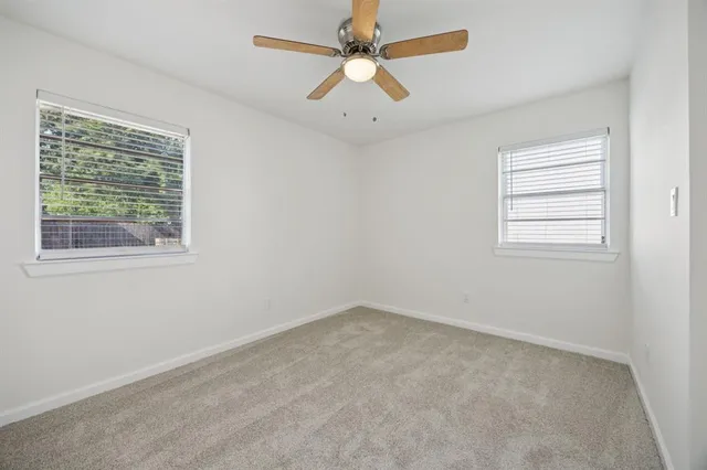 an empty room with a window and a fan