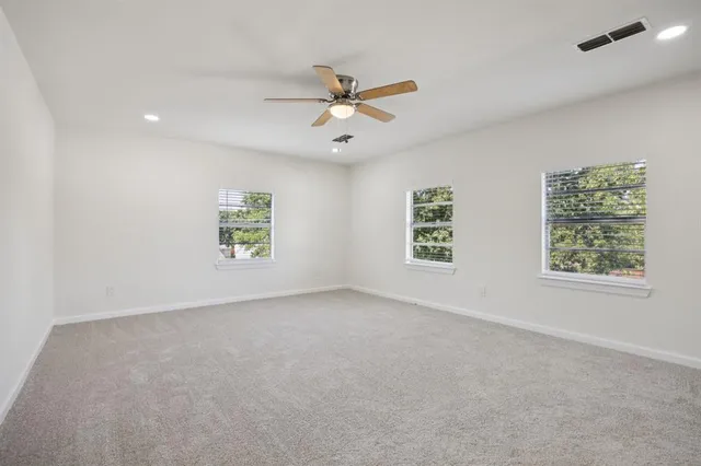 an empty room with windows and fan