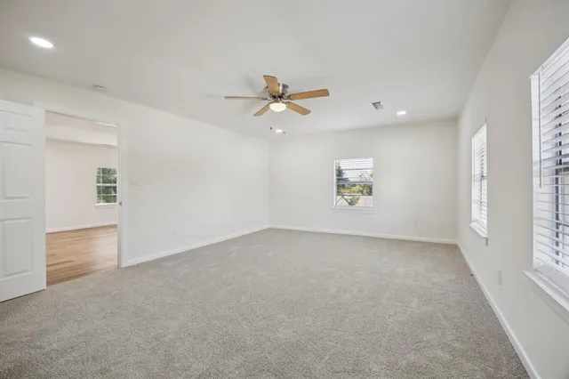 an empty room with chandelier fan and windows